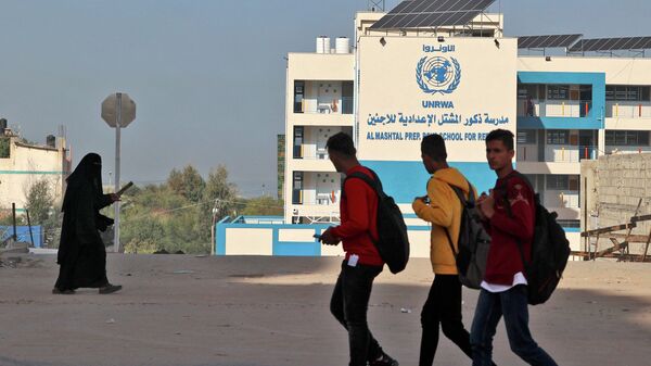 Palestinos passam pela sede fechada da Agência das Nações Unidas de Assistência aos Refugiados da Palestina no Próximo Oriente (UNRWA), na Cidade de Gaza, em 29 de novembro de 2021 - Sputnik Brasil