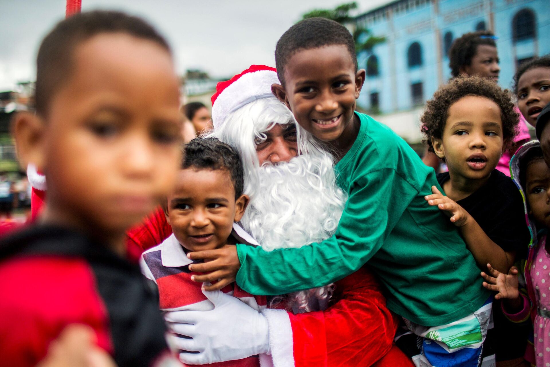 Crianças abraçam homem fantasiado de Papai Noel no Complexo do Alemão, Rio de Janeiro, 23 de dezembro de 2021 - Sputnik Brasil, 1920, 27.12.2021