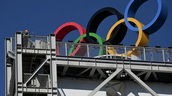 Um trabalhador pinta uma parte de um prédio onde os anéis olímpicos estão localizados no Parque Shougang, um dos locais dos Jogos Olímpicos de Inverno de Pequim 2022, 1º de dezembro de 2021 - Sputnik Brasil
