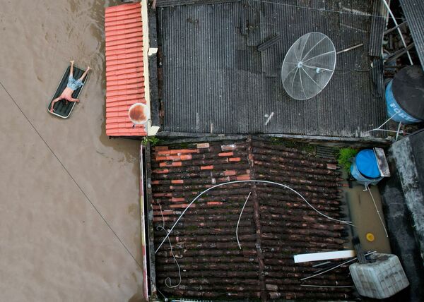 Homem usa colchão inflável durante inundações no Brasil. - Sputnik Brasil