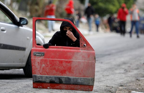 Manifestante palestino se esconde atrás de uma porta de carro durante protesto contra os assentamentos judaicos no povoado de Burqa, na Cisjordânia ocupada por Israel. - Sputnik Brasil