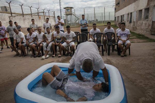 Ruben Muñoz, um pastor evangélico da igreja Porta do Céu, que cumpre uma pena de dois anos por roubo, batiza um preso em uma piscina infantil na Unidade Penal N11 em Pinero, Argentina. - Sputnik Brasil