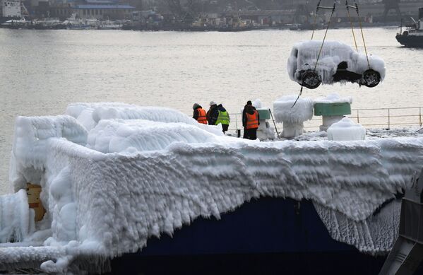 Descarga de veículos ligeiros, cobertos por espessa camada de gelo, de navio de transporte no porto de Vladivostok, Rússia. - Sputnik Brasil