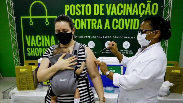 Em Osasco, no estado brasileiro de São Paulo, uma mulher é vacinada contra a COVID-19 enquanto segura um bebê, em 3 de janeiro de 2022 - Sputnik Brasil