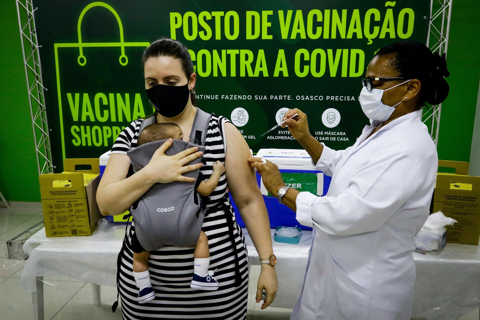 Em Osasco, no estado brasileiro de São Paulo, uma mulher é vacinada contra a COVID-19 enquanto segura um bebê, em 3 de janeiro de 2022 - Sputnik Brasil, 1920, 04.01.2022