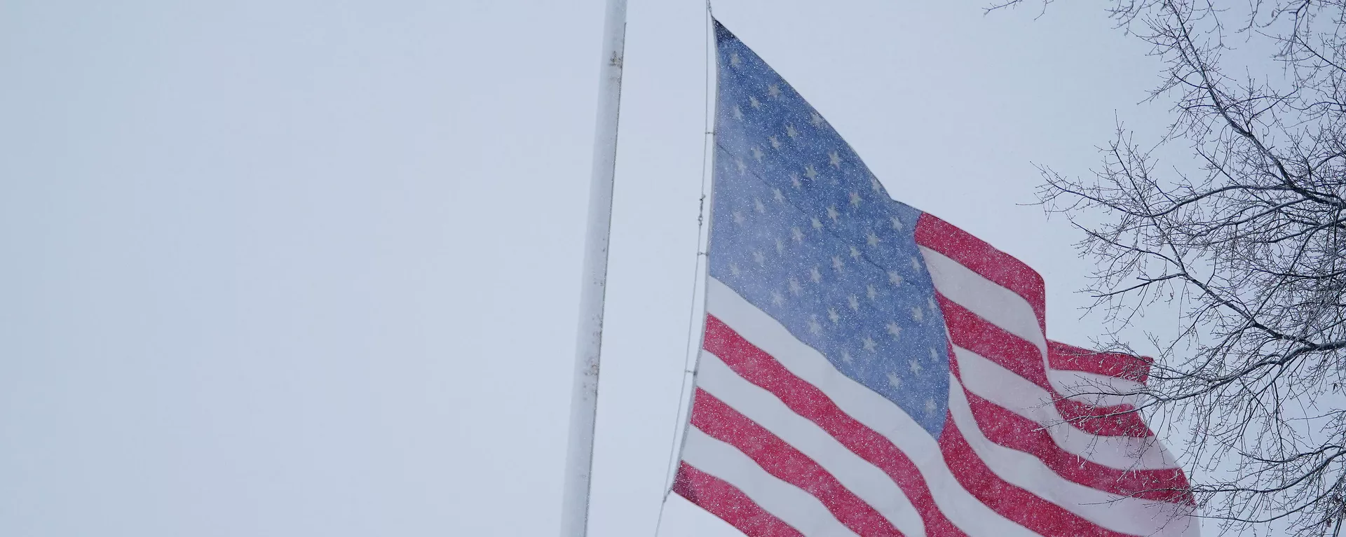 Em Baltimore, nos Estados Unidos, uma pessoa caminha em meio à neve perto de uma bandeira nacional, em 3 de janeiro de 2022 - Sputnik Brasil, 1920, 02.12.2023