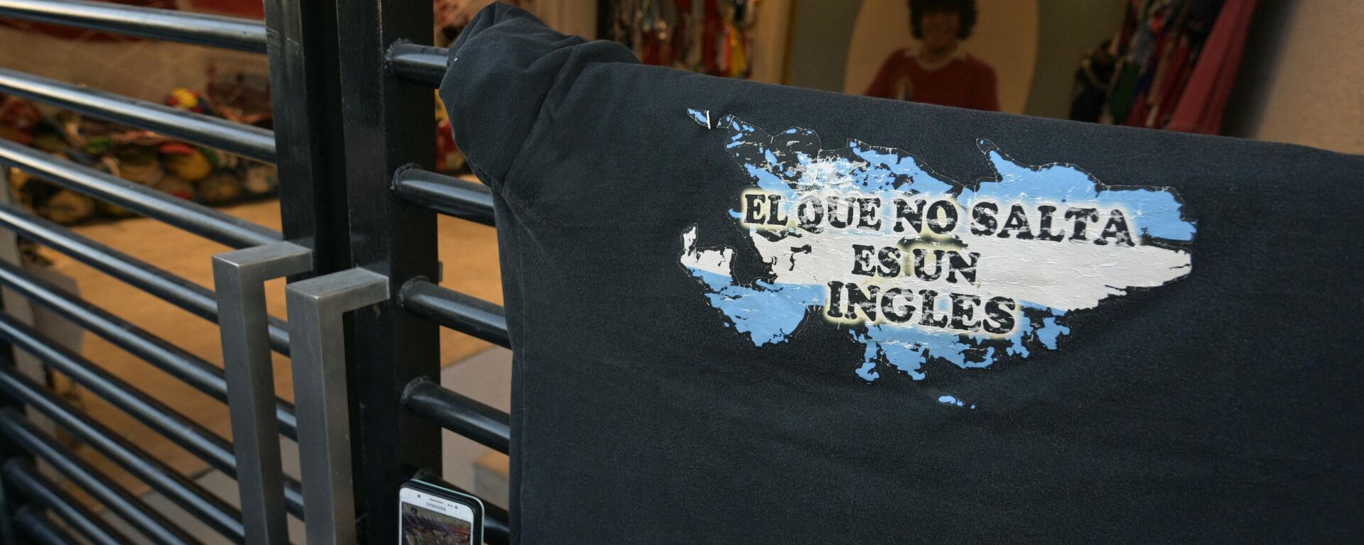 Pessoa tira fotografia de camisola com mapa das ilhas Malvinas dizendo: Quem não salta é inglês em Buenos Aires, Argentina, 22 de junho de 2021 - Sputnik Brasil, 1920, 04.01.2022