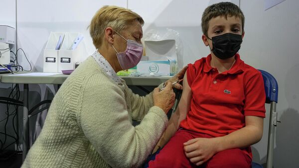 Uma profissional da saúde administra uma dose da vacina Pfizer contra a COVID-19 em uma criança de oito anos, em Saint-Quentin-en-Yvelines, a oeste de Paris, na França, no dia 22 de dezembro de 2021 - Sputnik Brasil