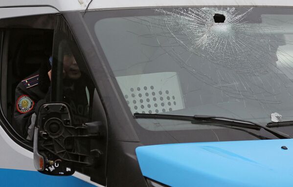 Policial dentro de caminhonete da polícia com vidro partido durante protestos contra a subida do preço de gás de petróleo liquefeito pelas autoridades cazaques, em Almaty, Cazaquistão, 5 de janeiro de 2022 - Sputnik Brasil