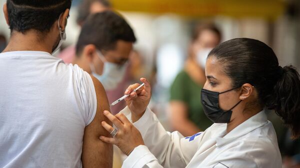 Em São Paulo, uma agente de saúde aplica uma dose de vacina contra a COVID-19 em um cidadão, em 16 de novembro de 2021 - Sputnik Brasil