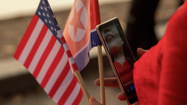 Nesta foto de arquivo de 27 de fevereiro de 2019, uma mulher segura as bandeiras dos EUA e da Coreia do Norte enquanto caminha em Hanói, no Vietnã - Sputnik Brasil