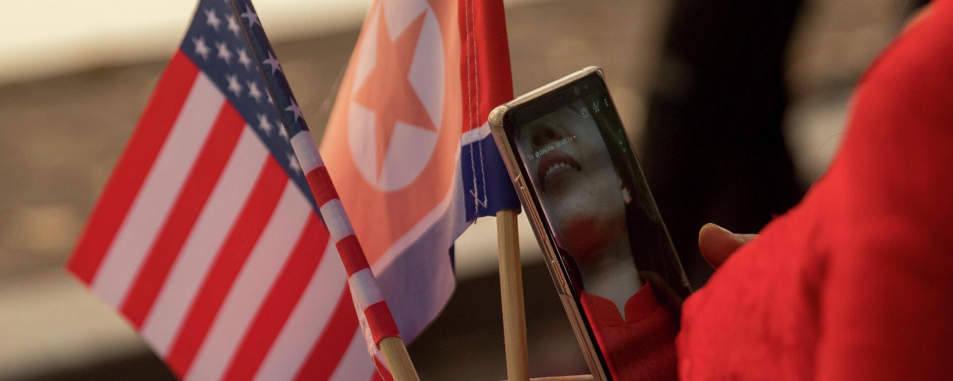 Nesta foto de arquivo de 27 de fevereiro de 2019, uma mulher segura as bandeiras dos EUA e da Coreia do Norte enquanto caminha em Hanói, no Vietnã - Sputnik Brasil, 1920, 29.06.2022
