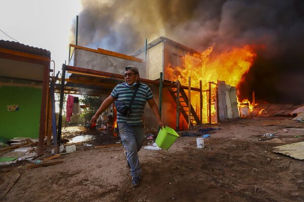 Morador ajuda a combater incêndio no bairro de baixa renda de Laguna Verde, Iquique, Chile, 10 de janeiro de 2022 - Sputnik Brasil