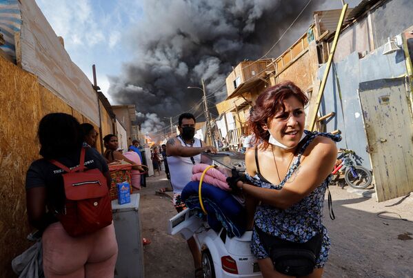 Residentes fogem com seus pertences durante incêndio no bairro de baixa renda de Laguna Verde, Iquique, Chile, 10 de janeiro de 2022 - Sputnik Brasil