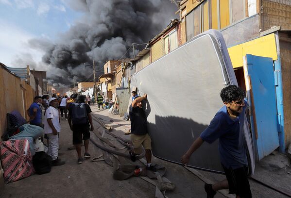 Moradores fugindo com seus pertences durante incêndio no bairro de baixa renda de Laguna Verde, Iquique, Chile, 10 de janeiro de 2022 - Sputnik Brasil