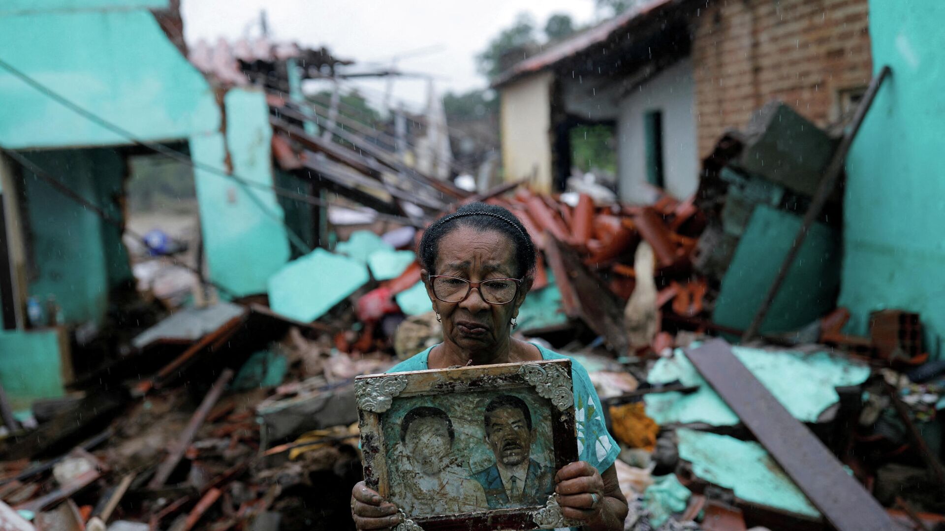 Em Itambé, no estado brasileiro da Bahia, Vitória Rocha, de 81 anos, segura uma foto de seus pais em frente aos escombros de sua casa destruída por enchentes, em 28 de dezembro de 2021 - Sputnik Brasil, 1920, 12.01.2022