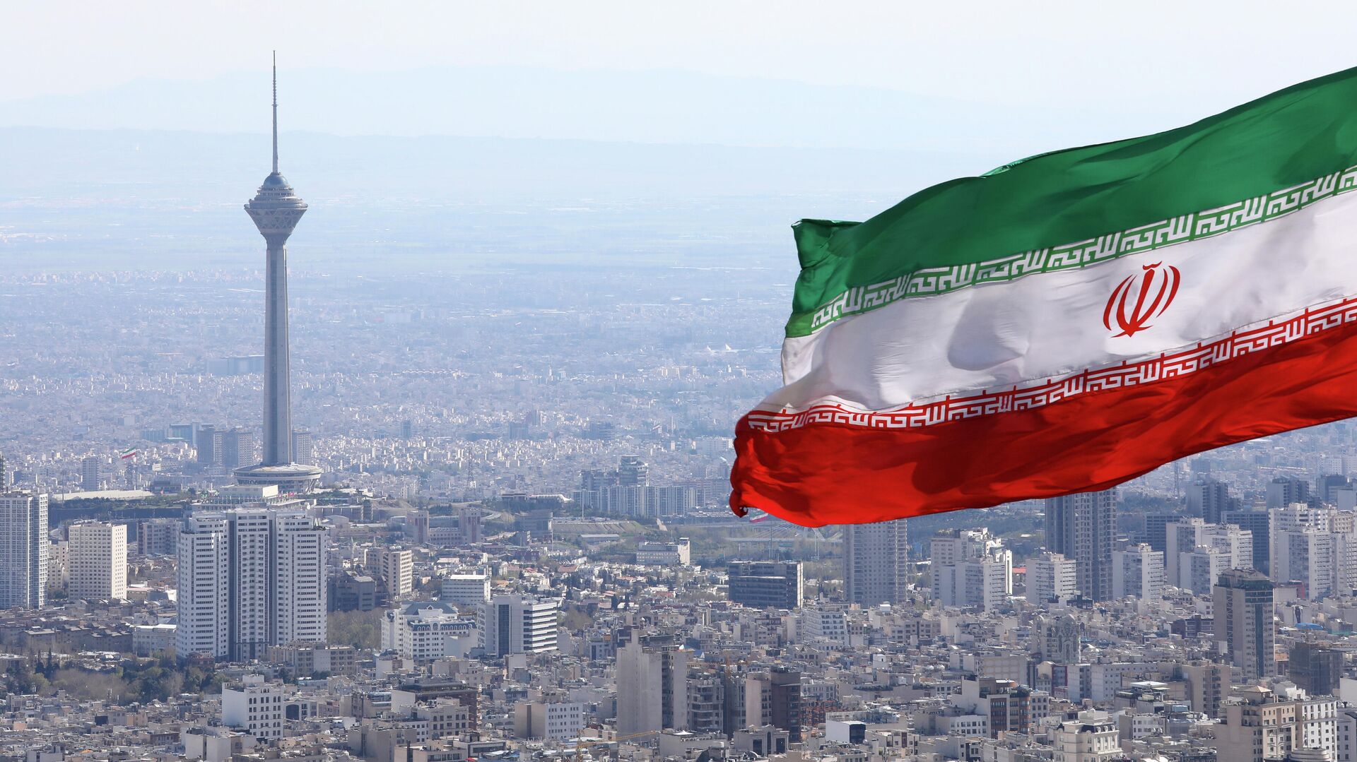 A bandeira nacional do Irã acena como a torre de telecomunicações Milad e a bandeira nacional do buildinIran acena quando os togs de telecomunicações Milad são vistos em Teerã, Irã, terça-feira, 31 de março de 2020 - Sputnik Brasil, 1920, 10.02.2024
