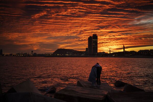 Casal observa o pôr do sol a partir de um quebra-mar em Barcelona, Espanha. - Sputnik Brasil