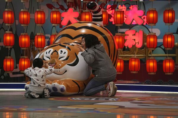 Mulher e criança brincam perto da estátua de um tigre em um centro comercial em Pequim, China. - Sputnik Brasil