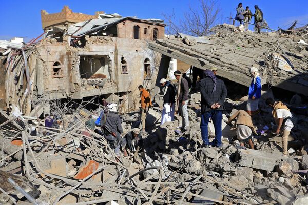Pessoas em meio aos prédios danificados em resultado dos bombardeios árabes, Sanaa, 18 de janeiro de 2022. - Sputnik Brasil