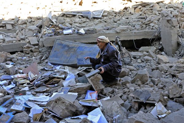Homem sentado entre os escombros de um prédio destruído em resultado dos ataques aéreos pela coalizão árabe contra Sanaa. Iêmen, 18 de janeiro de 2022. - Sputnik Brasil