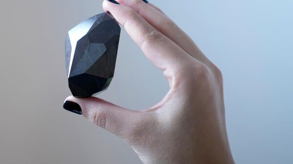 Uma funcionária da Sotheby's Dubai apresenta o diamante negro de 555,55 quilates O Enigma para ser leiloado na galeria Sotheby's Dubai, em Dubai, Emirados Árabes Unidos, segunda-feira, 17 de janeiro de 2022 - Sputnik Brasil