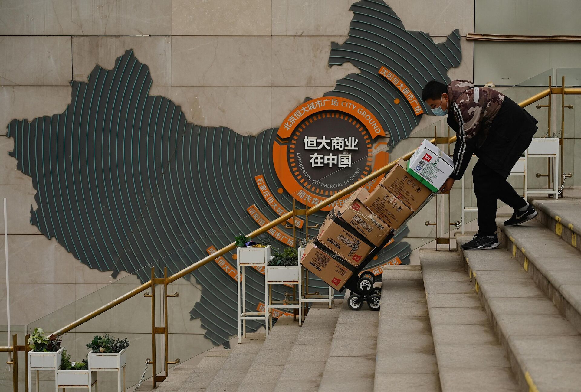 Trabalhador empurra carrinho em frente a placa que mostra a operação do Evergrande Group na China, em complexo habitacional do incorporador imobiliário em Pequim, em 8 de dezembro de 2021 - Sputnik Brasil, 1920, 18.01.2022