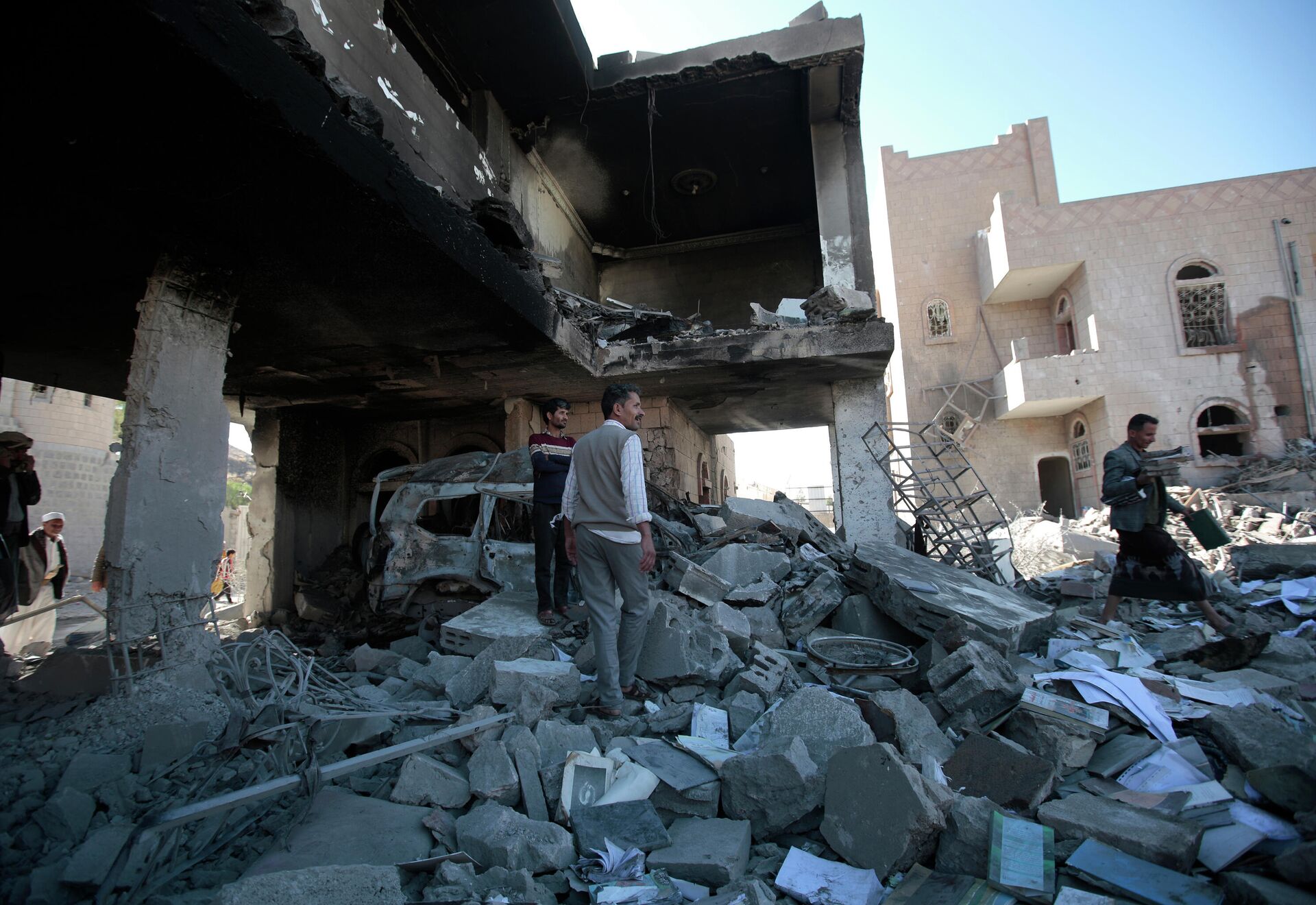 Pessoas inspecionam os destroços de edifícios que foram danificados por ataques aéreos da coalizão liderada pela Arábia Saudita, em Sanaa, Iêmen, terça-feira, 18 de janeiro de 2022 - Sputnik Brasil, 1920, 05.02.2022