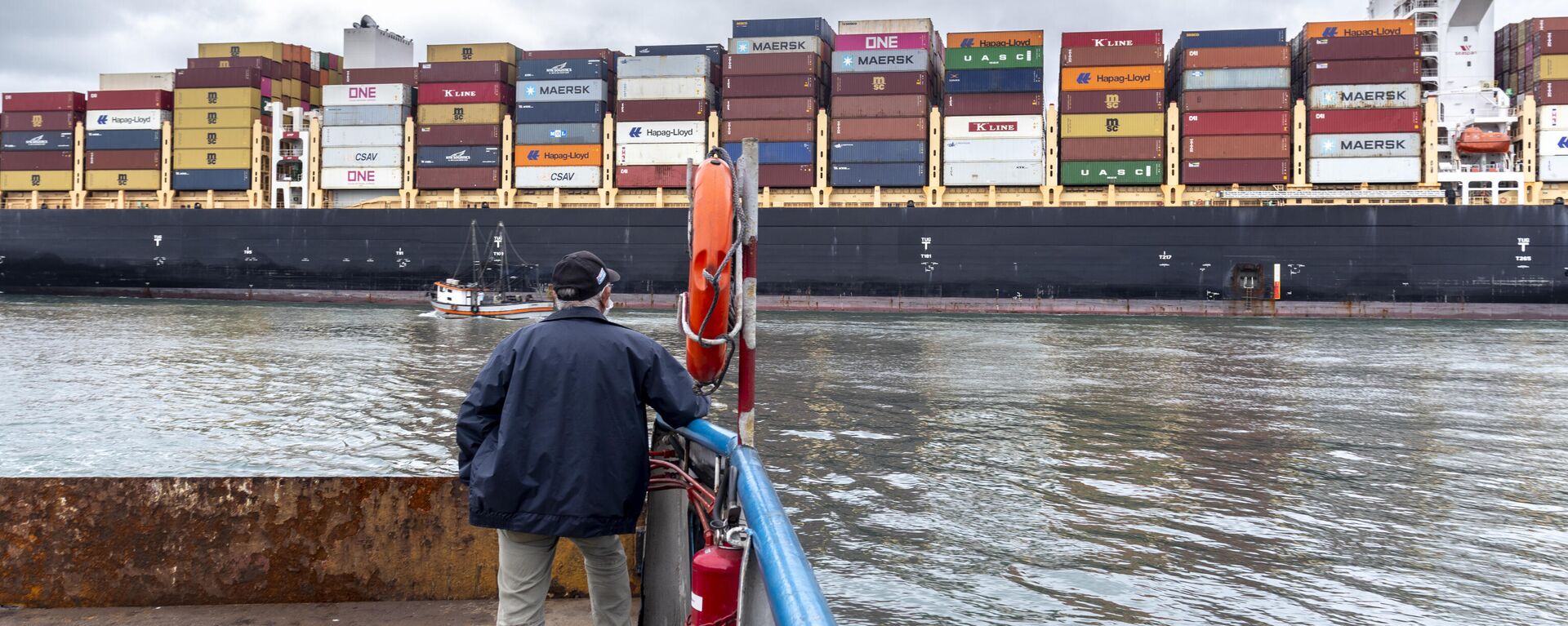 Em Santos, no estado brasileiro de São Paulo, homem observa cargueiro proveniente de Hong Kong sendo rebocado pelo canal do Porto de Santos, em 17 de setembro de 2021 - Sputnik Brasil, 1920, 21.01.2022