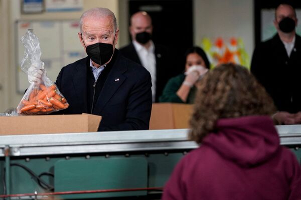Presidente dos EUA, Joe Biden, coloca um saco de cenouras na caixa de uma organização de combate à fome na Filadélfia. - Sputnik Brasil