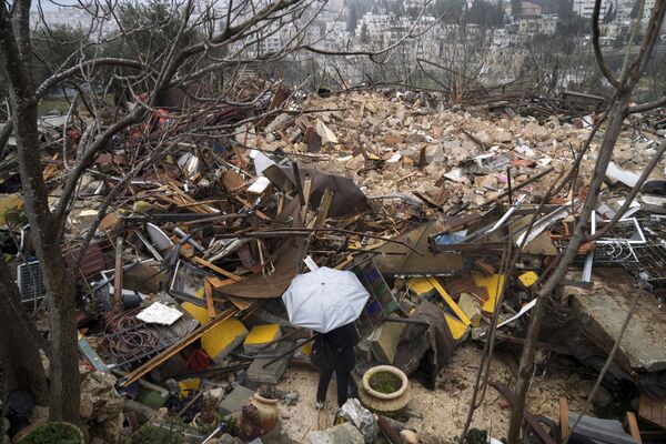 Mulher olha para as ruínas de uma casa palestina demolida pelo município de Jerusalém, no bairro de Sheikh Jarrah, em Jerusalém Oriental. - Sputnik Brasil