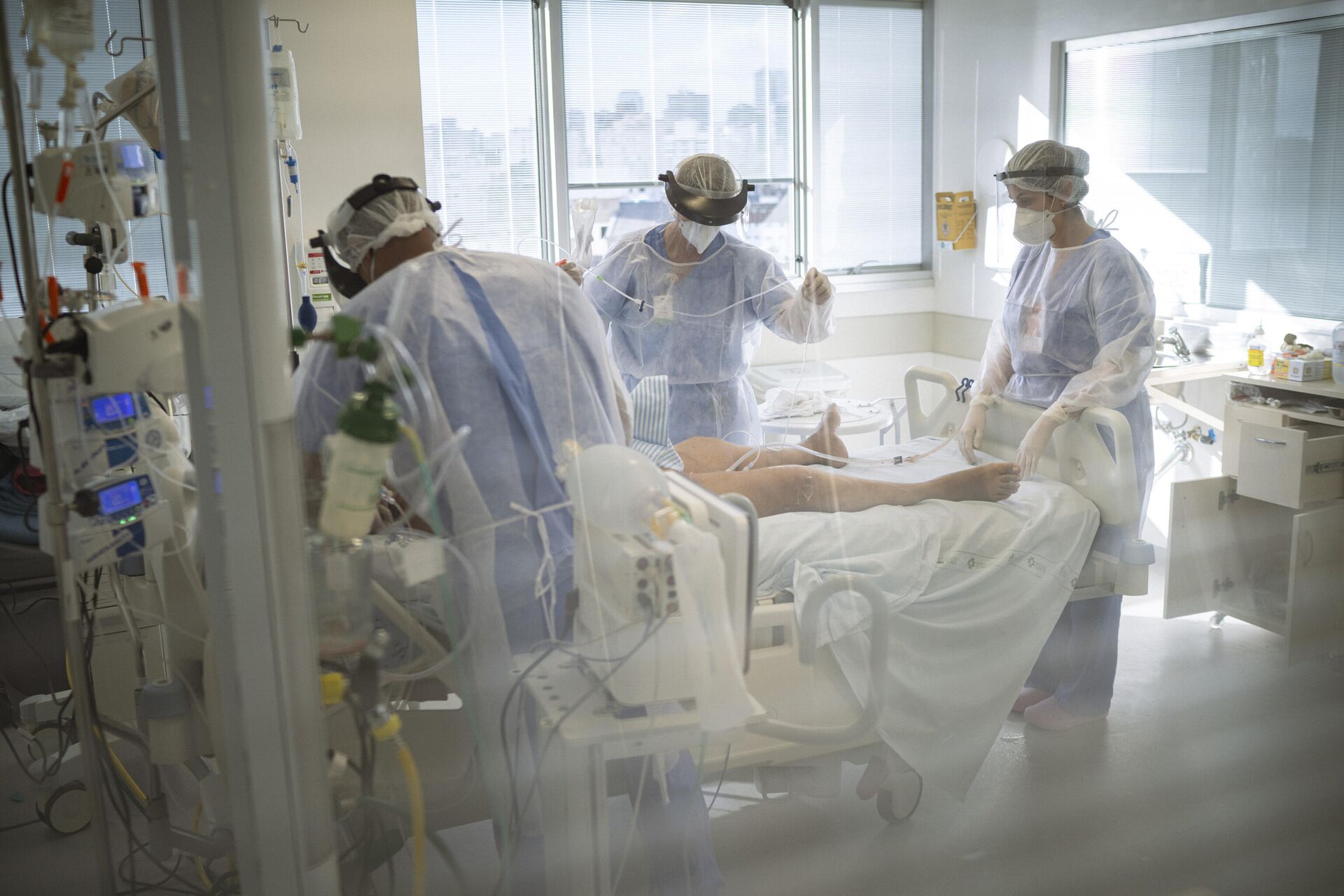 Em Porto Alegre, médicos e enfermeiros atendem um paciente com COVID-19 em uma UTI do Hospital das Clínicas, em 12 de março de 2021 - Sputnik Brasil, 1920, 28.01.2022