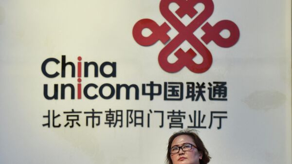Em Pequim, uma mulher caminha em frente a um anúncio da China Unicom, empresa chinesa estatal de telecomunicações, em 17 de agosto de 2017 - Sputnik Brasil