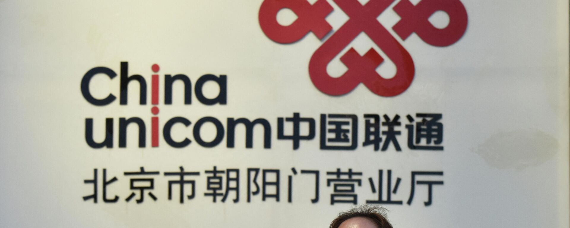 Em Pequim, uma mulher caminha em frente a um anúncio da China Unicom, empresa chinesa estatal de telecomunicações, em 17 de agosto de 2017 - Sputnik Brasil, 1920, 28.01.2022