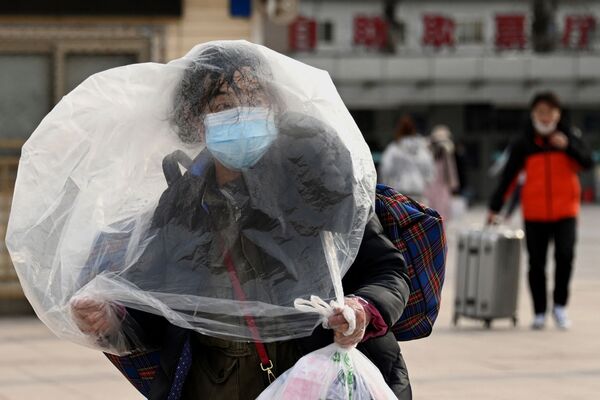 Mulher caminha no exterior de estação ferroviária em Pequim, China, 26 de janeiro de 2022 - Sputnik Brasil