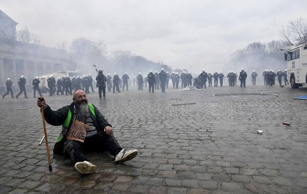 Homem sentado no pavimento durante confronto entre policiais e manifestantes em protesto contra restrições da COVID-19 em Bruxelas, Bélgica, 23 de janeiro de 2022 - Sputnik Brasil