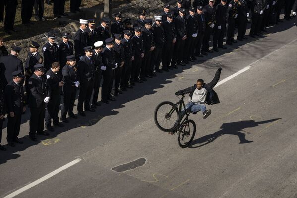 Homem anda de bicicleta após cerimônia fúnebre de três bombeiros mortos em Baltimore, Maryland, EUA. - Sputnik Brasil