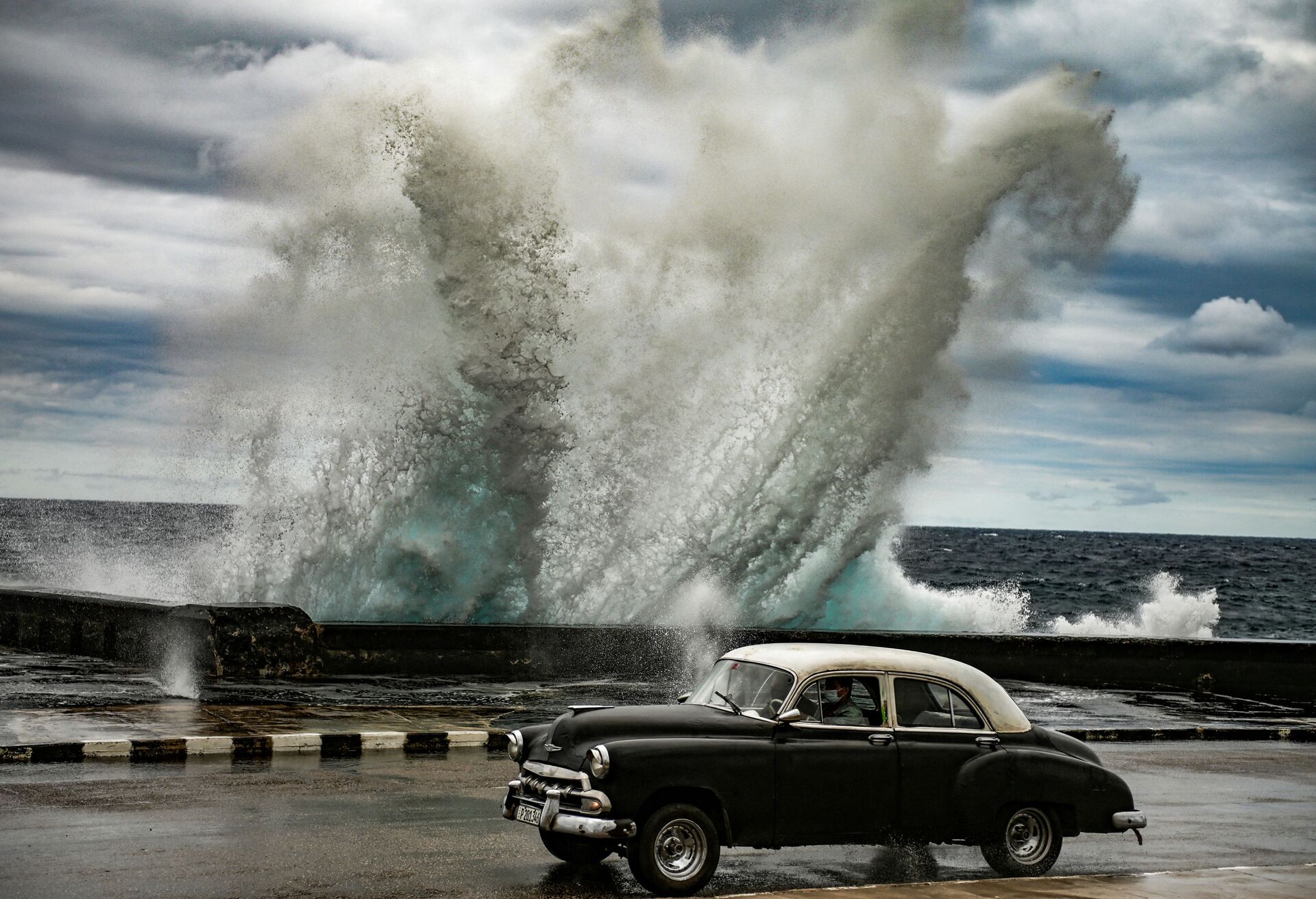 Um velho carro de fabricação norte-americana passa ao lado de uma onda gigante em Havana, Cuba 
 - Sputnik Brasil, 1920, 09.03.2022