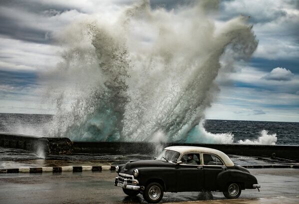 Um velho carro de fabricação norte-americana passa ao lado de uma onda gigante em Havana, Cuba. - Sputnik Brasil