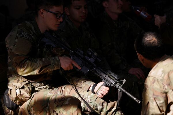 Um soldado da 82ª Divisão Aerotransportada do Exército dos EUA verifica sua arma enquanto espera para embarcar em um avião de transporte com destino à Europa, em Fort Bragg, Carolina do Norte, EUA, 14 de fevereiro de 2022. - Sputnik Brasil