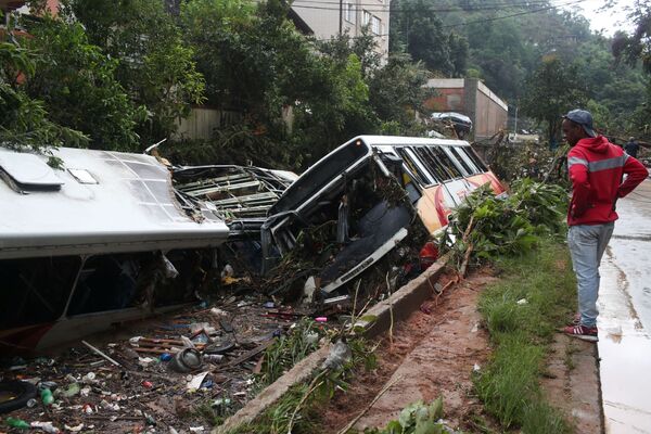 Homem observa ônibus públicos destruídos em um rio após chuvas torrenciais em Petrópolis, Brasil, em 16 de fevereiro de 2022. - Sputnik Brasil