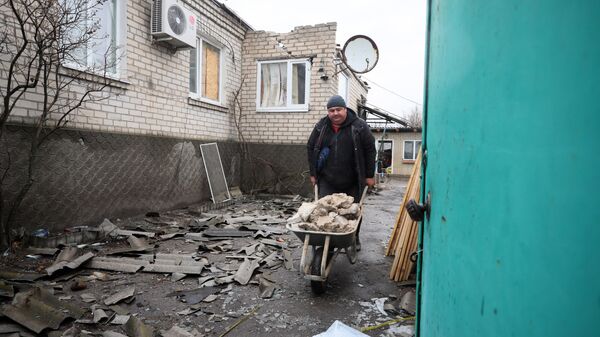 Um morador de Lugansk limpa detritos de casas, em 18 de fevereiro de 2022, em meio aos conflitos na região - Sputnik Brasil
