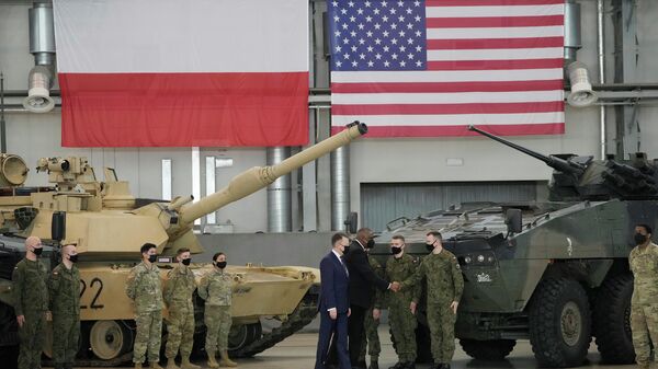 Secretário de Defesa dos EUA, Lloyd Austin, ao centro, e o ministro da Defesa da Polônia, Mariusz Blaszczak, em primeiro plano, apertam as mãos de soldados, durante uma visita às tropas dos EUA estacionadas na Base Aérea de Powidz, na Polônia, em 18 de fevereiro de 2022.  - Sputnik Brasil