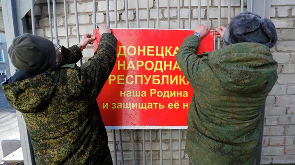 Militares da autoproclamada República Popular de Donetsk pendurando faixa nas portas de uma escola que diz: A República Popular de Donetsk é nossa pátria e nós devemos defendê-la!, Donetsk, 19 de fevereiro de 2022 - Sputnik Brasil