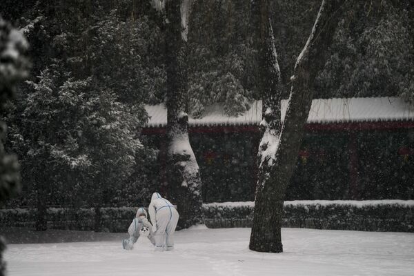 Trabalhadores usando trajes de proteção brincam com neve durante Jogos Olímpicos de Inverno em Pequim, China, 13 de fevereiro de 2022 - Sputnik Brasil