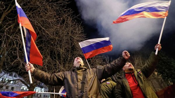 Pessoas com bandeiras russas lançam fogos de artifício nas ruas de Donetsk após Rússia ter reconhecido a independência das repúblicas de Donbass, 21 de fevereiro de 2022 - Sputnik Brasil