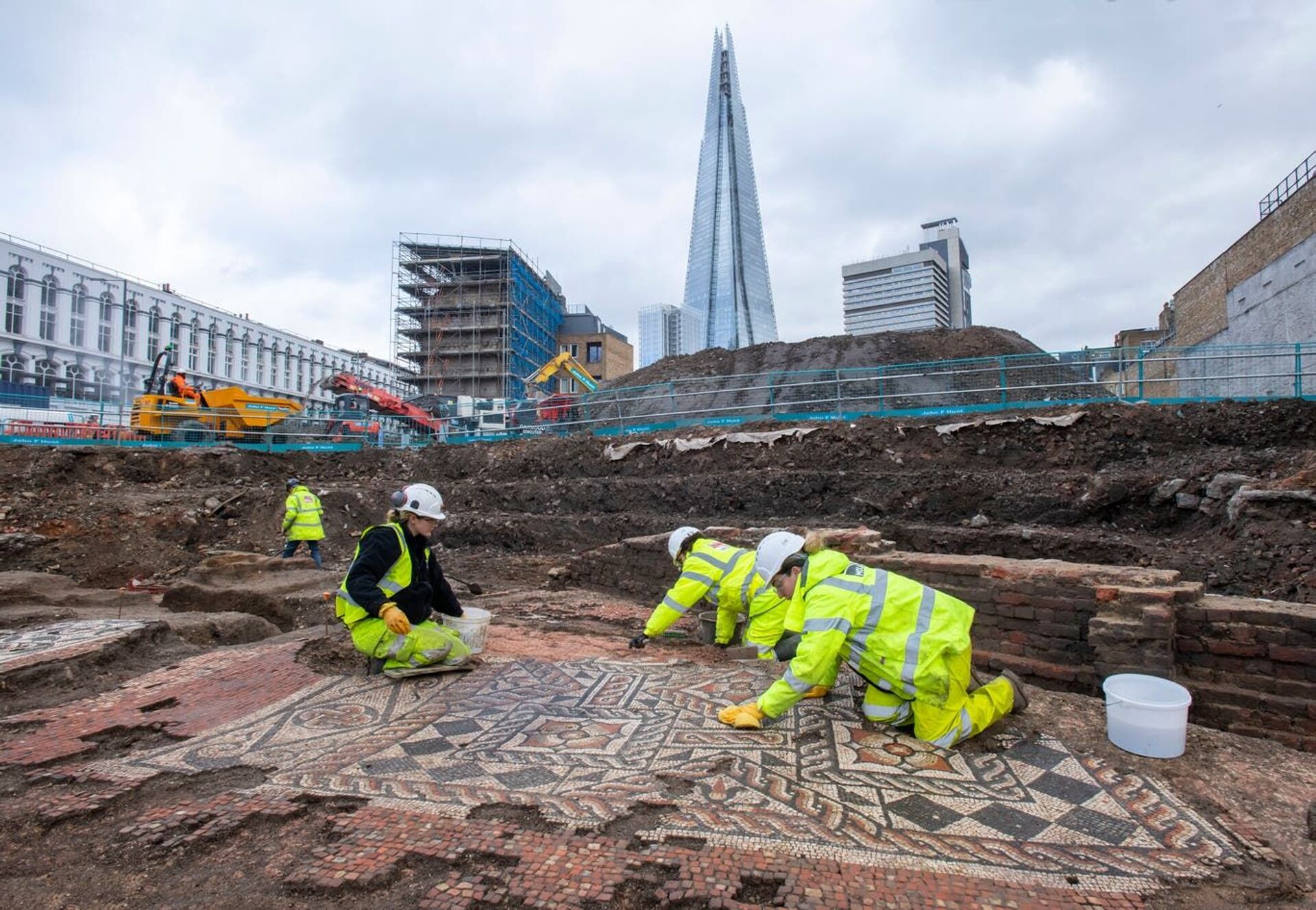 Arqueólogos trabalhando no sítio arqueológico onde foram descobertos mosaicos antigos em Southwark, Londres, com o edifício comercial Shard ao fundo - Sputnik Brasil, 1920, 23.02.2022