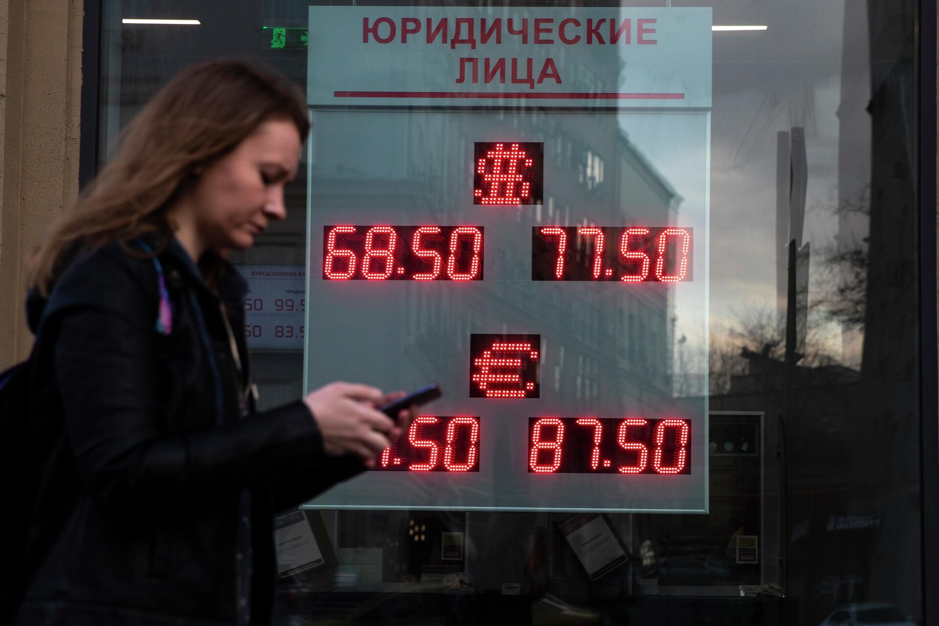 Uma mulher passa por uma tela de uma casa de câmbio exibindo as taxas de câmbio de dólar americano e euro para rublos russos, em Moscou, Rússia, 9 de março de 2020 - Sputnik Brasil, 1920, 22.04.2022