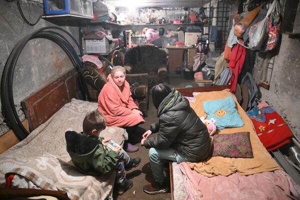 Mulher se esconde com crianças em porão de uma casa dos disparos das Forças Armadas da Ucrânia em Gorlovka - Sputnik Brasil