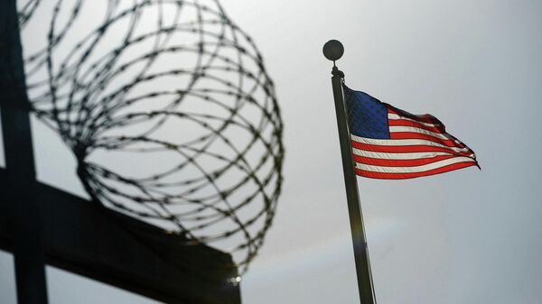 Uma bandeira dos EUA tremula acima de uma cerca de arame farpado no centro de detenção Camp Six (acampamento seis) na Estação Naval dos EUA na Baía de Guantánamo, 10 de dezembro de 2008 - Sputnik Brasil